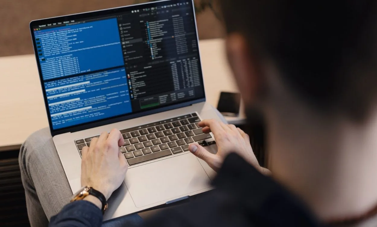 Person working on a laptop with code displayed on the screen, focused on software development tasks.