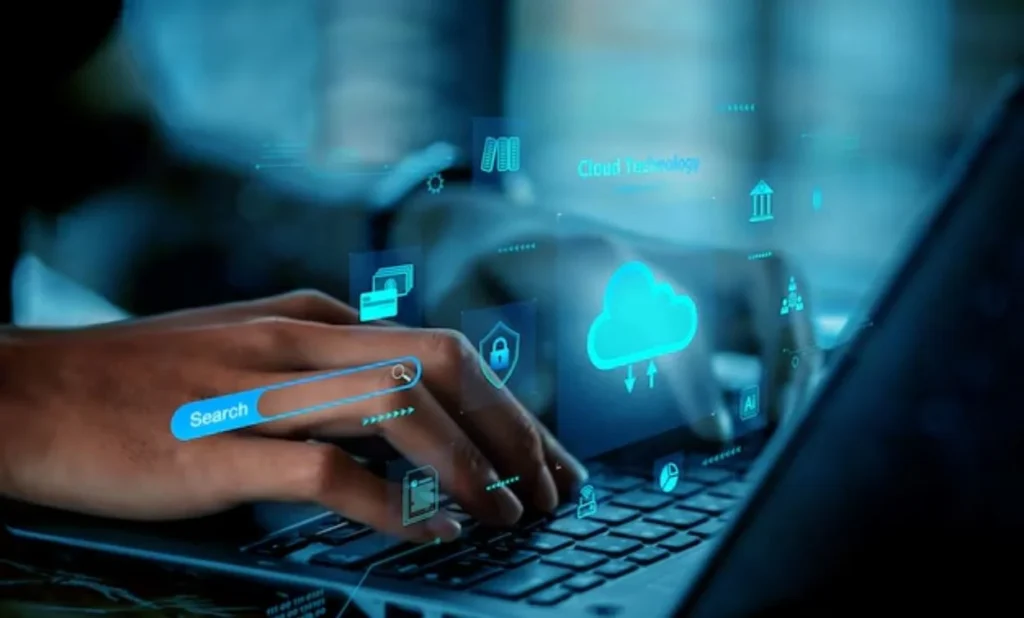 Hands typing on a laptop with floating holographic icons for cloud computing, cybersecurity, AI, and digital data.