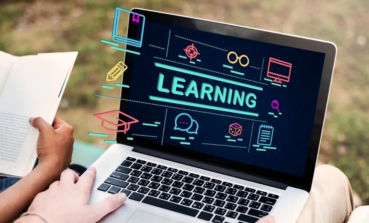 Person using a laptop for online learning with digital education icons displayed on screen representing e-learning and skill development.