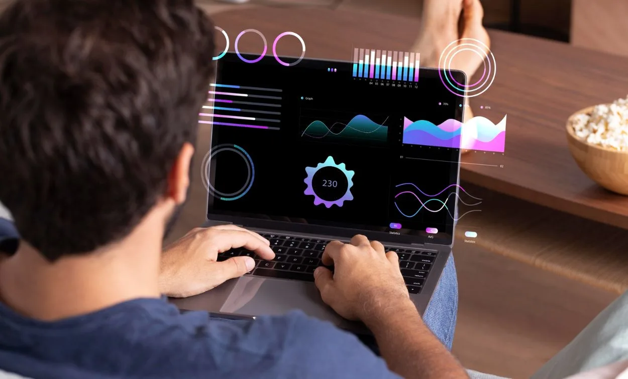 Person working on a laptop displaying colorful data analytics charts and digital graphs.