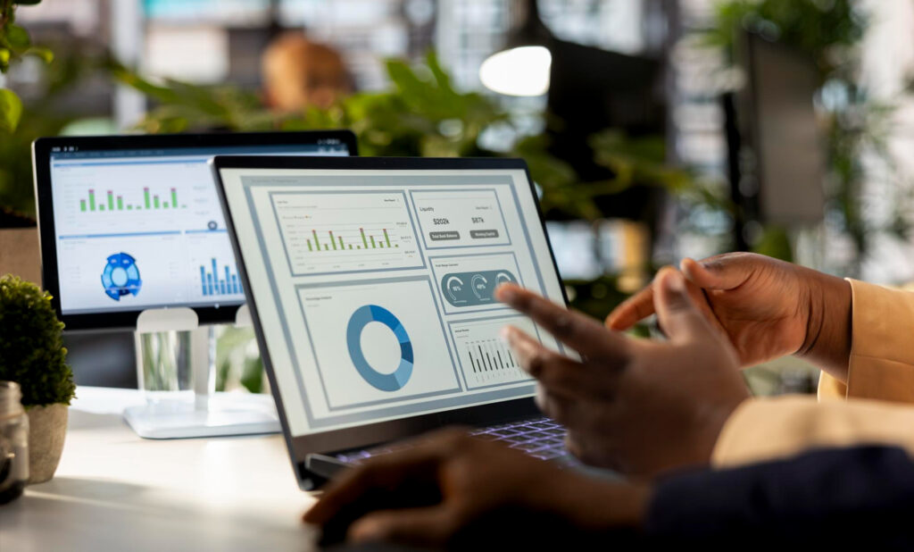Data analyst reviewing charts, graphs, and business dashboards on a laptop in an office.